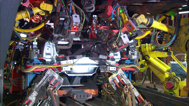 随着火花飞溅，汽车机器人在装配线上焊接汽车零件。视频素材