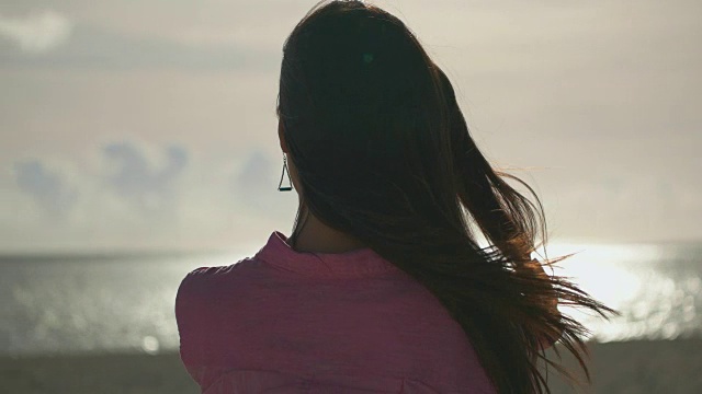 年轻的日本女性站在那里望着大海。视频下载