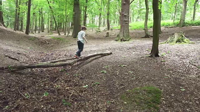 一个在圆木上保持平衡的小男孩视频素材