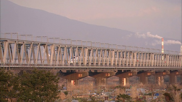 一列子弹头列车驶过一座可以俯瞰富士山的桥。视频素材