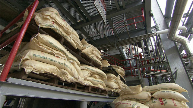 在一家工厂里，大袋子的肥料覆盖着地板和低矮的货架。视频下载