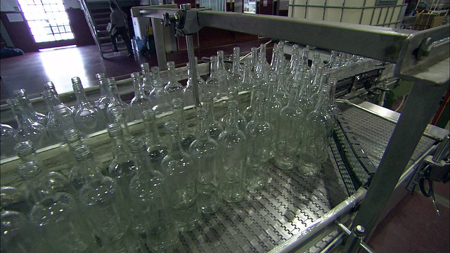 在朗姆酒装瓶厂，透明的瓶子沿着拥挤的传送带移动。视频素材