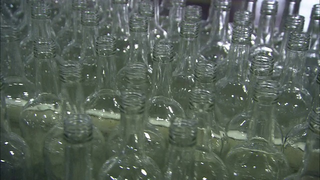 透明的朗姆酒瓶子在拥挤的传送带上移动。视频素材