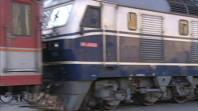 一列红蓝相间的火车驶离车站。视频下载