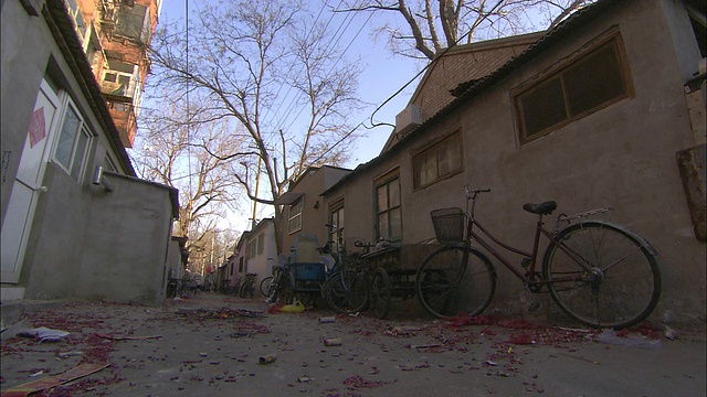 垃圾吹过一条小巷，一辆自行车和摇摇欲坠的家具倚在一所房子上。视频素材