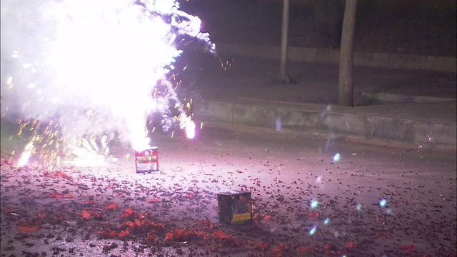 一个参加庆典的人点燃了一个烟花，另一个烟花射向天空。视频下载