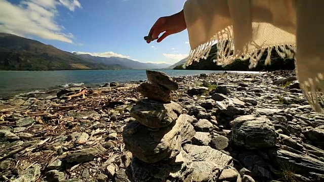 日出时人在湖边堆积岩石的细节视频素材