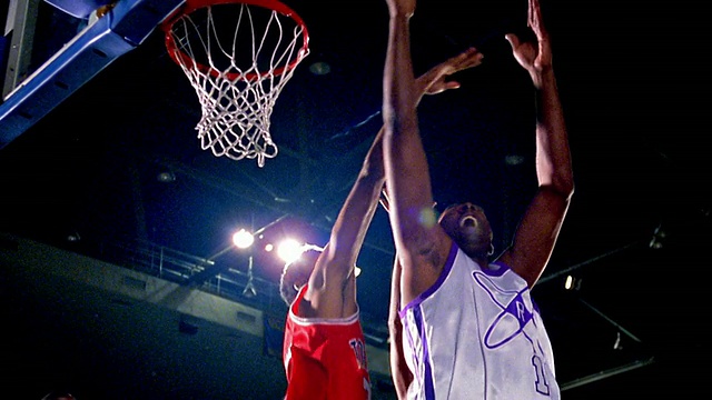 慢动作MS低角度两支男子篮球队在队服中跳起争夺篮板球的失球视频下载