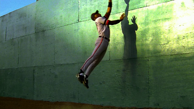 慢镜头:黑色外野手跳跃+在绿墙上接住棒球视频素材