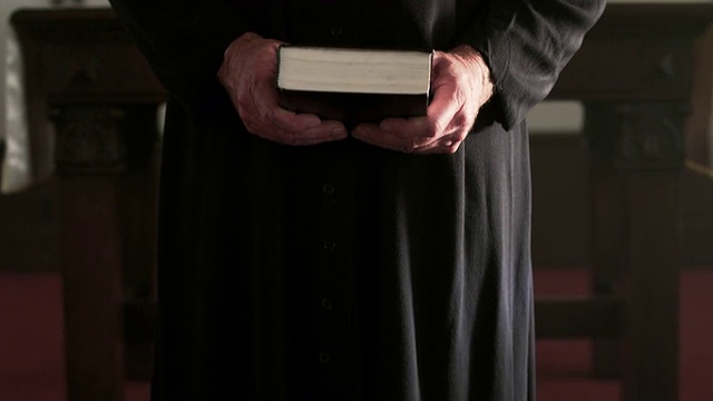 牧师站着，等待着，手里拿着一本书。视频下载