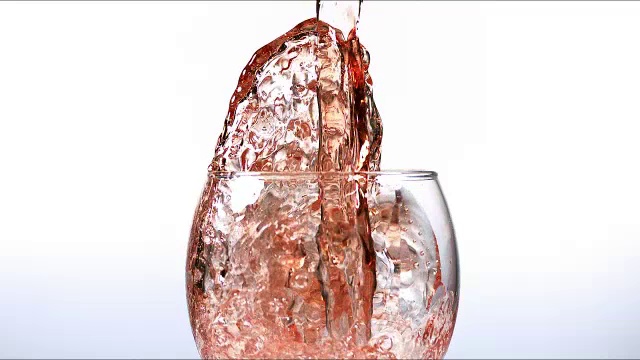 “白色背景下，将粉红葡萄酒倒入杯中，慢动作”视频下载