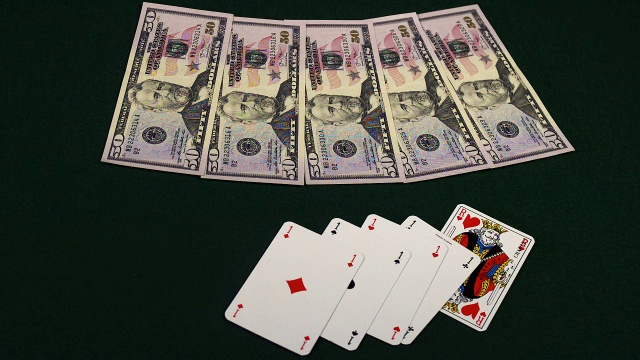 “黑色背景下，扑克牌落在美钞上的慢动作”视频下载