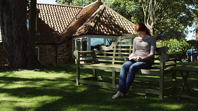 在花园长凳上看书的女人视频素材