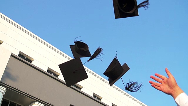 同学们把毕业礼帽抛向空中庆祝。视频下载