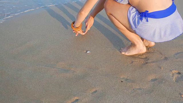 女孩用手在沙滩上画心形视频下载