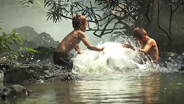 亚洲男孩在河里玩得很开心，一起溅水视频素材