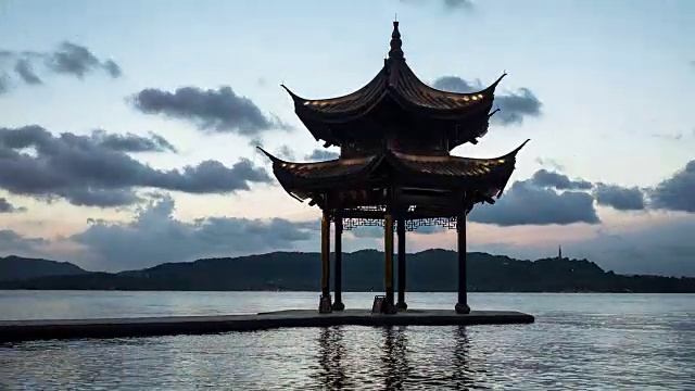 从白天到夜晚4K延时:灯光逐渐照亮中国杭州西湖上的亭子视频素材
