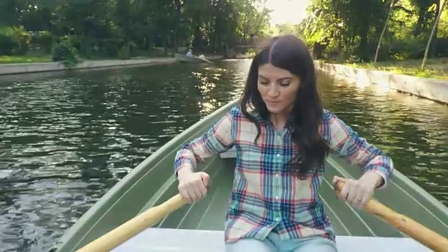 女人在一个美丽的阳光明媚的日子里划船。视频下载