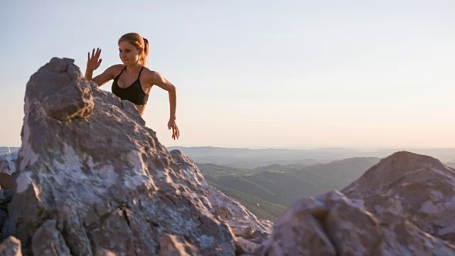 年轻的女性跑步者在岩石上奔跑视频素材