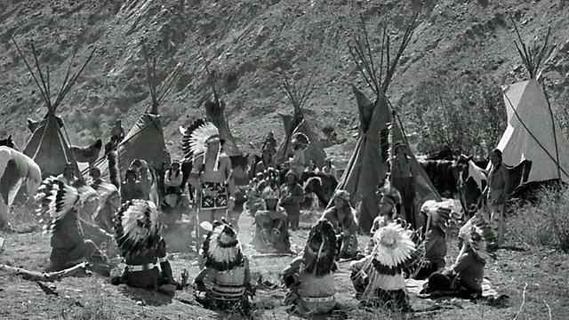 B/W 19世纪广角拍摄的印第安人围坐在一起，背景是一个人在说话+打手势/圆锥形帐篷视频下载