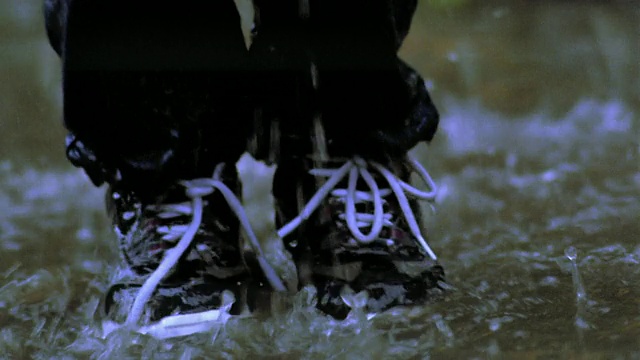 近孩子的脚跳在泥泞的水坑视频素材