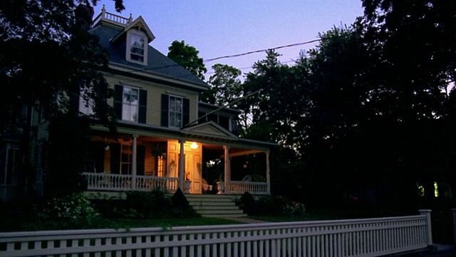宽镜头PAN门廊+房子灯在郊区的房子黄昏打开视频素材