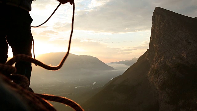 登山家横越到悬崖边，太阳在后面升起视频素材