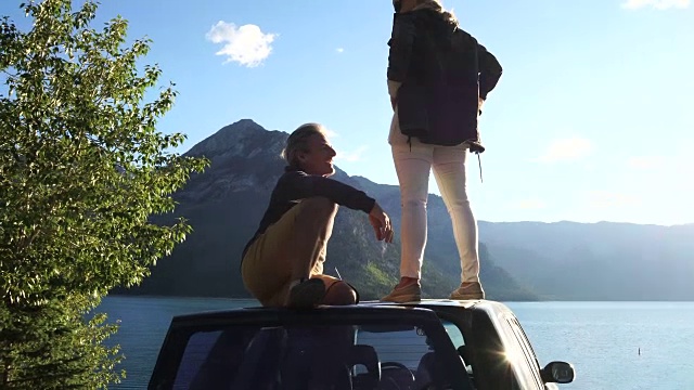 日出时分，一对夫妇乘车停在山湖边视频素材