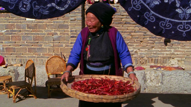 MS资深白族妇女在户外的篮子里扔红辣椒/大理，云南，中国视频下载