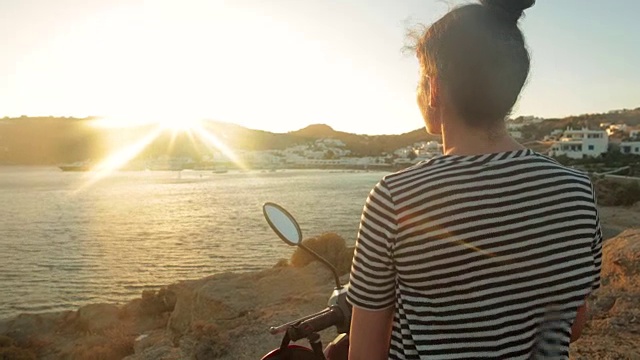 坐在摩托车上欣赏海景的女人。视频素材