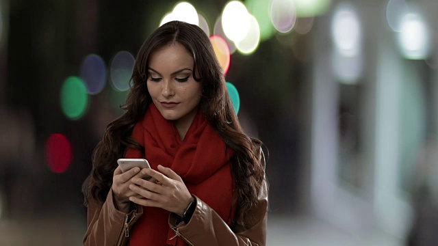一名年轻女子在街上用智能手机发短信和大笑视频素材