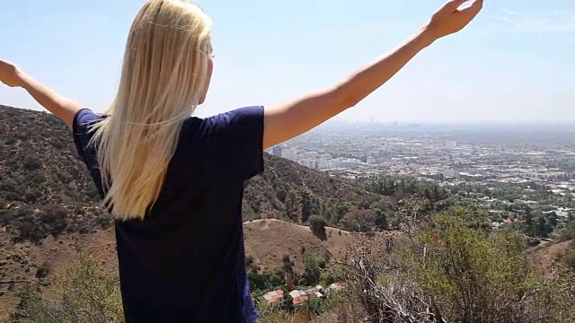 一位年轻女子站在加州洛杉矶附近好莱坞山的一座山上，张开双臂视频素材