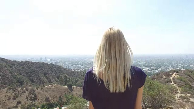 一名年轻女子站在洛杉矶附近的一座山上的4K航拍，4K胶片视频素材