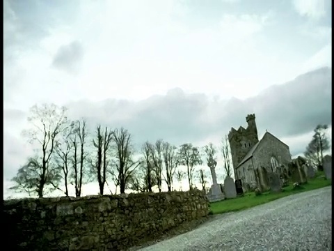 3个男孩在乡村道路上奔跑，经过教堂+墓地/爱尔兰视频素材