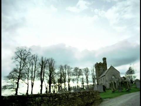 高对比度广角拍摄PAN乡村道路与教堂+墓地的背景/爱尔兰视频素材