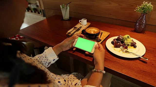 在咖啡店用绿屏手机的女人视频素材