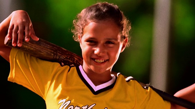 肖像女孩穿着棒球服微笑，肩膀上有棒球棒/佛罗里达视频素材