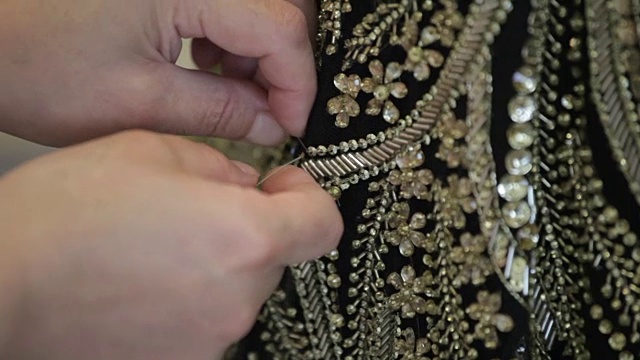 一个人把珠子缝在衣服上的特写。视频下载