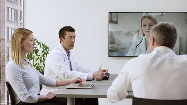 一组医生正在和一位女同事进行视频电话会议视频素材