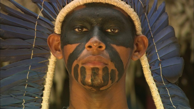 一个土著男子戴着头饰，身体和脸上涂着颜料。视频下载