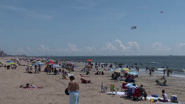 康尼岛海滩在一个炎热的夏天下午，飞机拖着横幅在海滩上视频素材