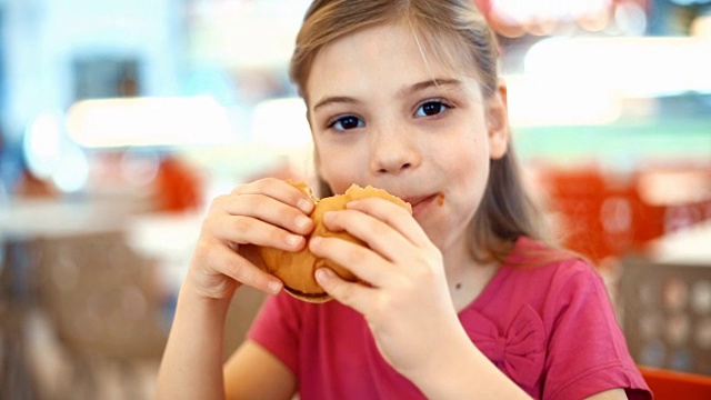 小女孩在吃汉堡。视频下载