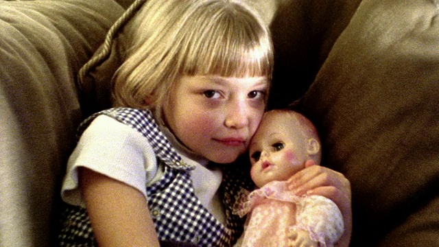 摇晃的MS肖像年轻的金发女孩躺在沙发上拥抱+亲吻娃娃视频素材