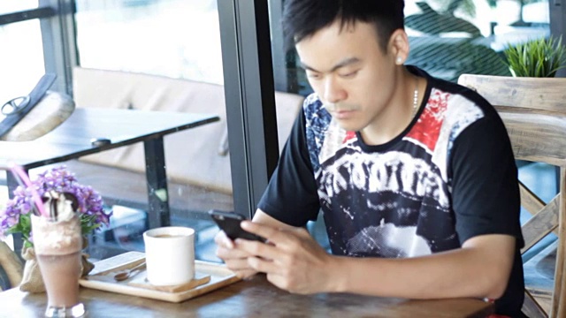 一名男子在咖啡店里打智能手机视频素材