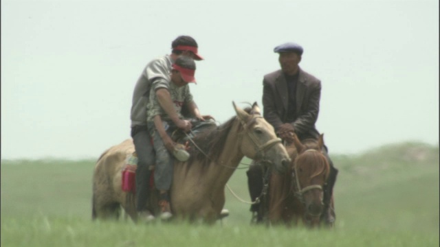在巴音布鲁克草原上，放牧人骑在马背上。视频下载