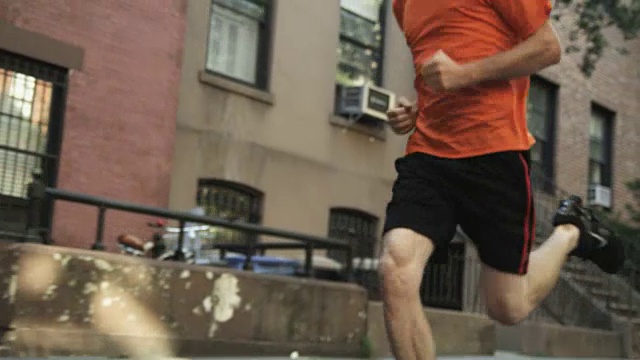 一个男人沿着曼哈顿街道慢跑的低角度镜头。视频下载