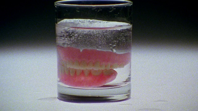 将假牙放入装有气泡片的玻璃杯中视频素材