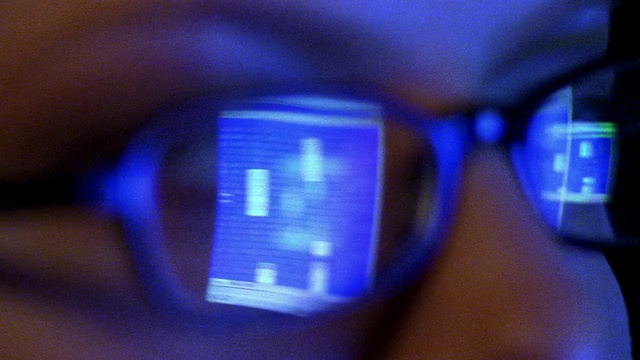 极度接近女人的脸，电脑屏幕上的电子表格反射在眼镜上视频下载