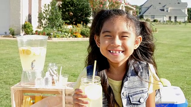可爱的亚洲小女孩在柠檬水摊位前微笑视频下载