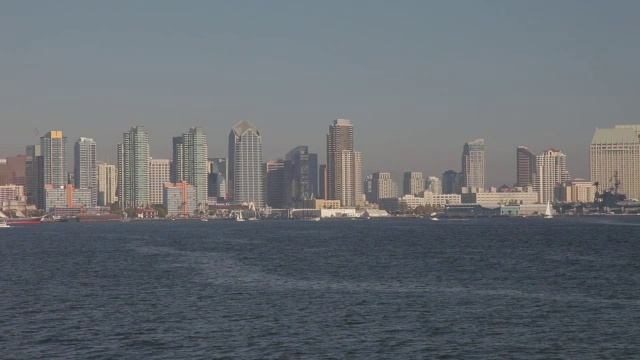 潘从右到左从圣地亚哥-科罗纳多大桥到摩天大楼和高层的办公室或公寓大楼在城市天际线。港口或海湾里的帆船。视频素材